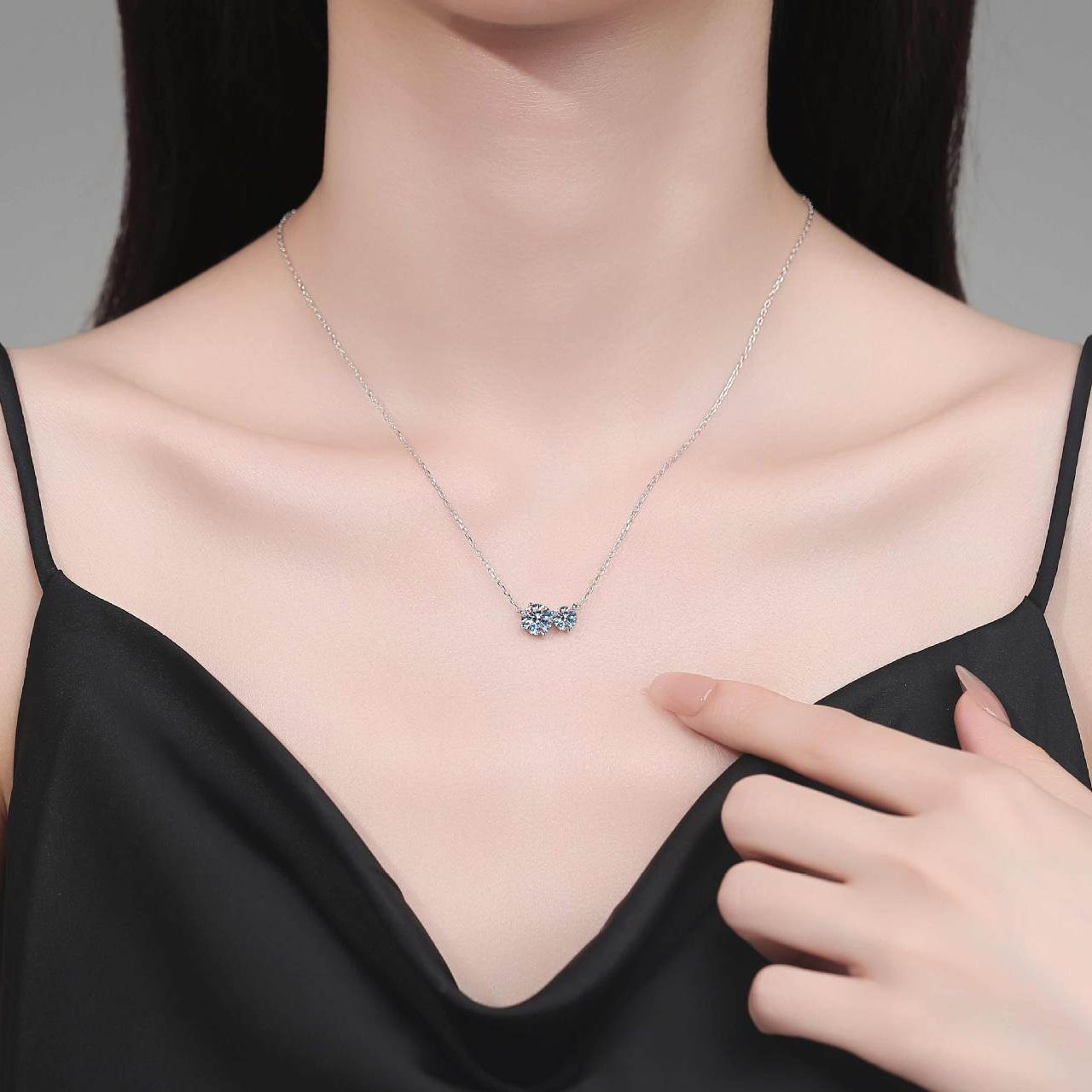 Woman wearing a black top with a necklace featuring a blue gemstone.