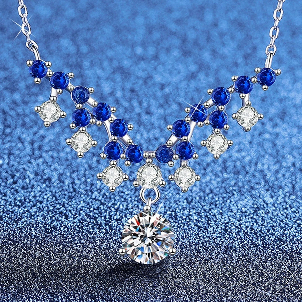 Blue Accent Graduated Moissanite Drop Necklace with Cubic Zirconia in Platinum-Plated S925 Sterling Silver blue background angled view