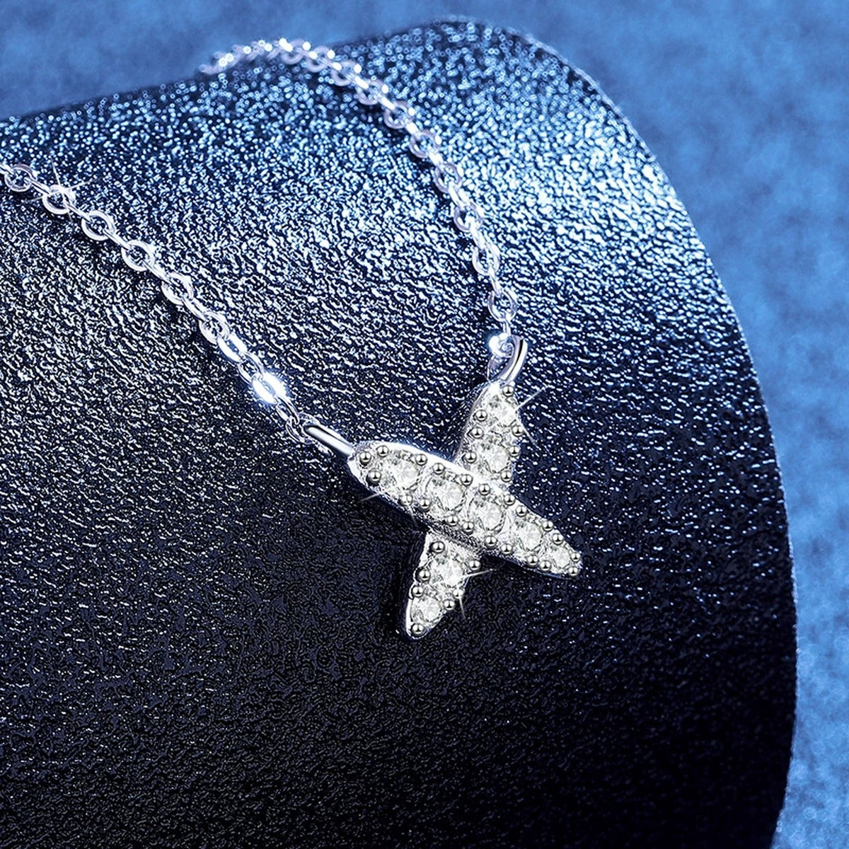 X Motif Moissanite Pendant Necklace in Platinum-Plated S925 Sterling Silver blue background angled view