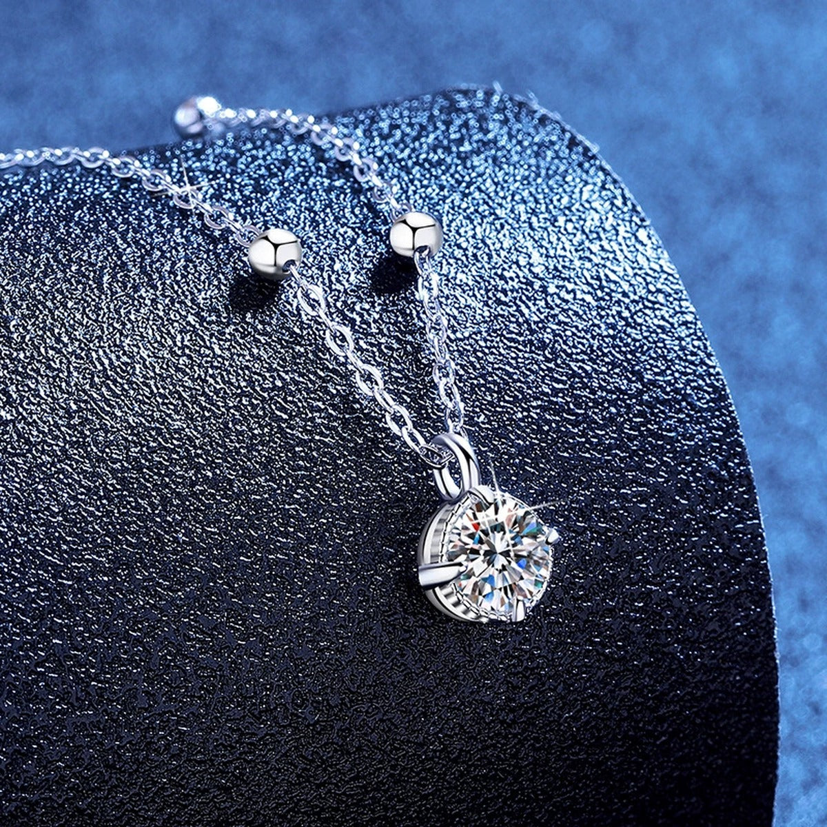 Solitaire Moissanite Pendant Necklace in Platinum-Plated S925 Sterling Silver blue background angled view
