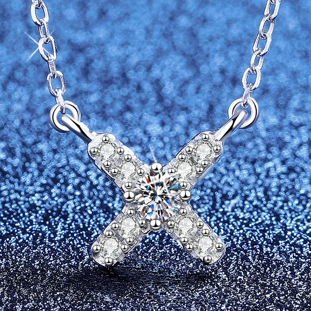 Petite X Moissanite Pendant Necklace with Cubic Zirconia in Platinum-Plated S925 Sterling Silver blue background angled view