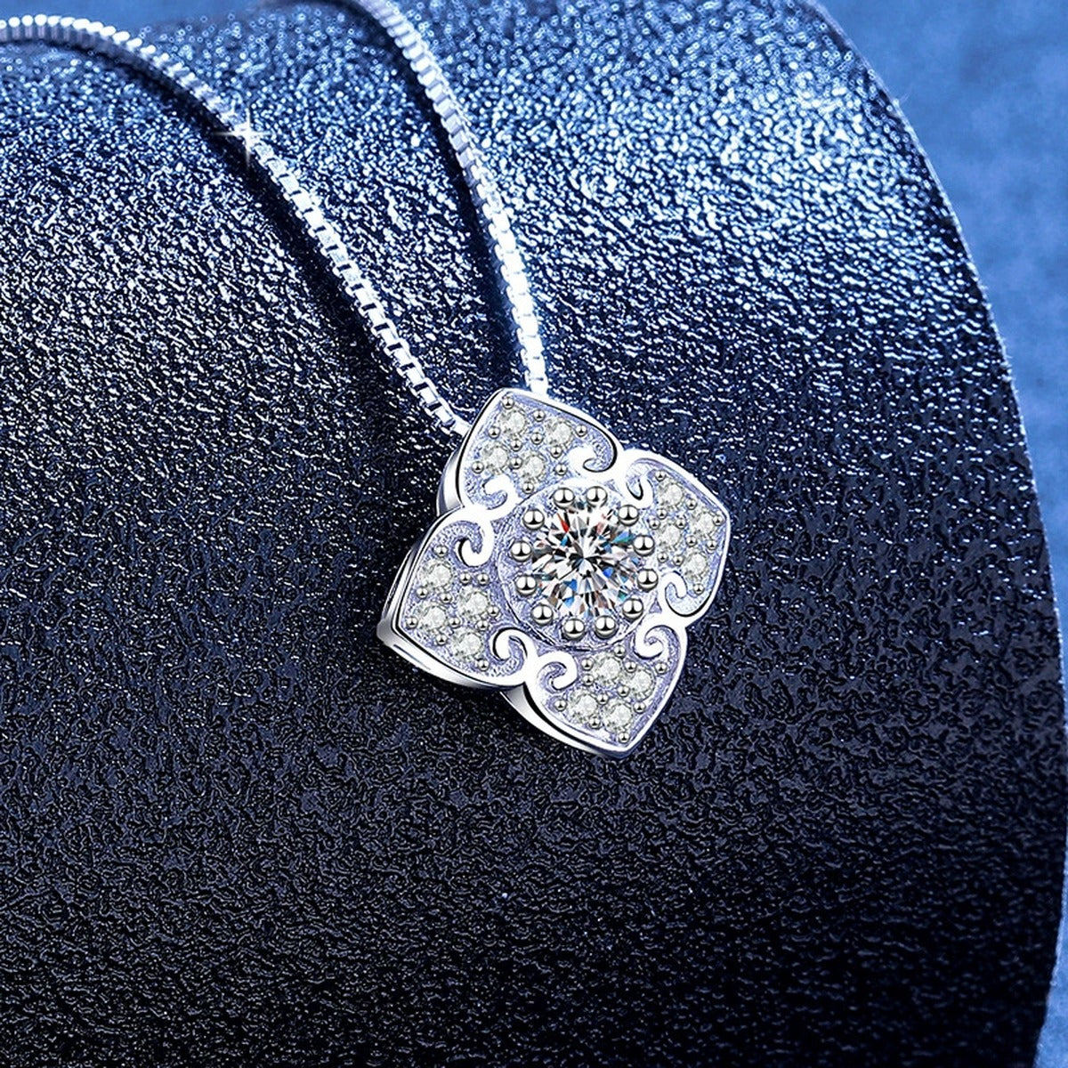 Quatrefoil Clover Moissanite Pendant Necklace with Cubic Zirconia in Platinum-Plated S925 Sterling Silver blue background angled view