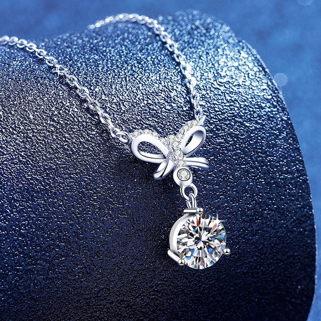 Bow round moissanite pendant necklace styled on blue display