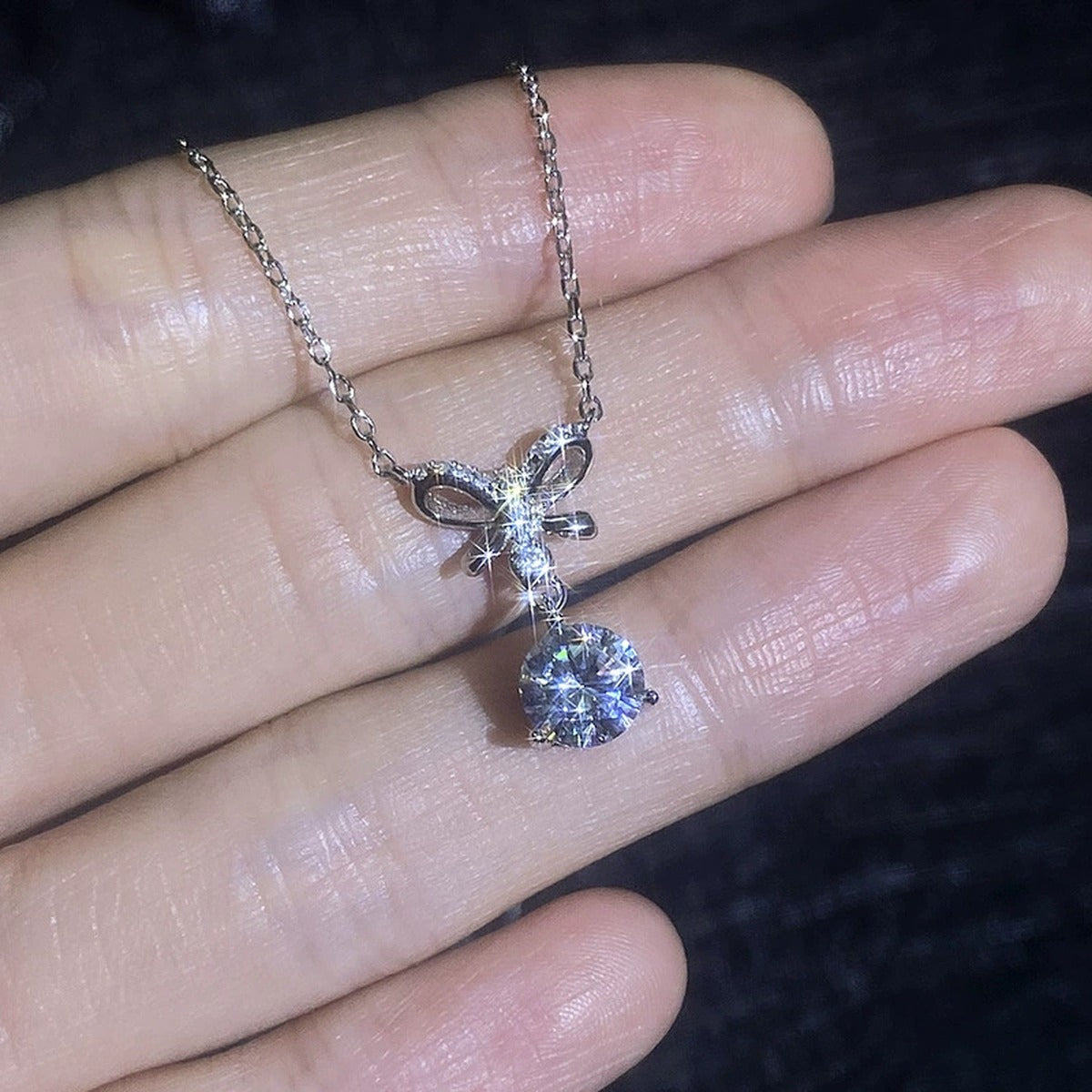 Bow moissanite pendant necklace shown in hand