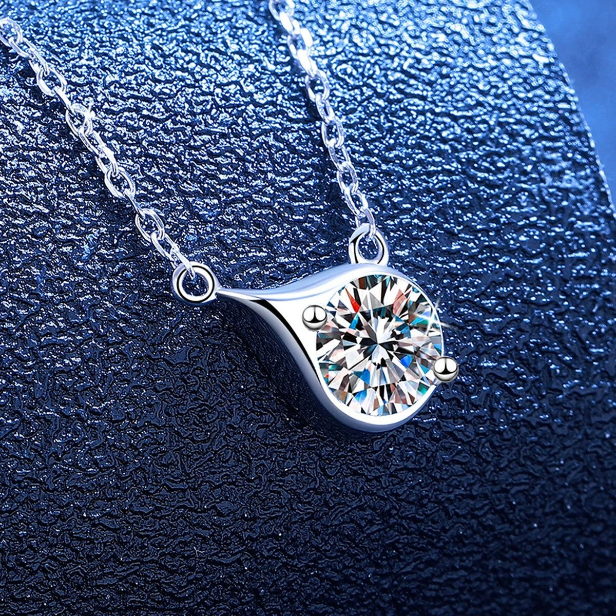 Swirl moissanite pendant necklace styled on blue display