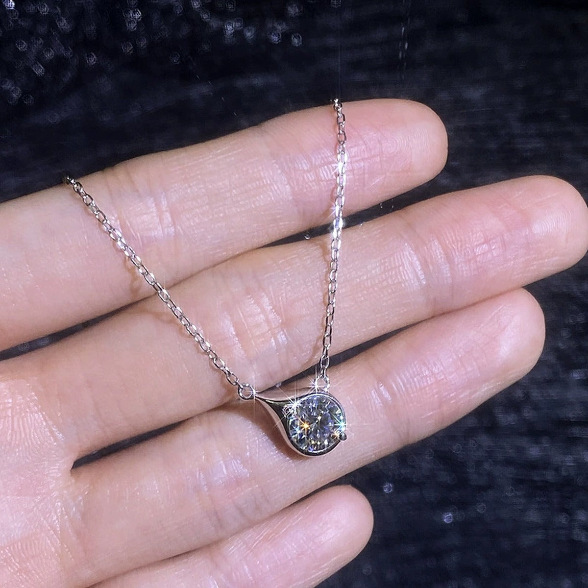 Swirl moissanite pendant necklace shown in hand