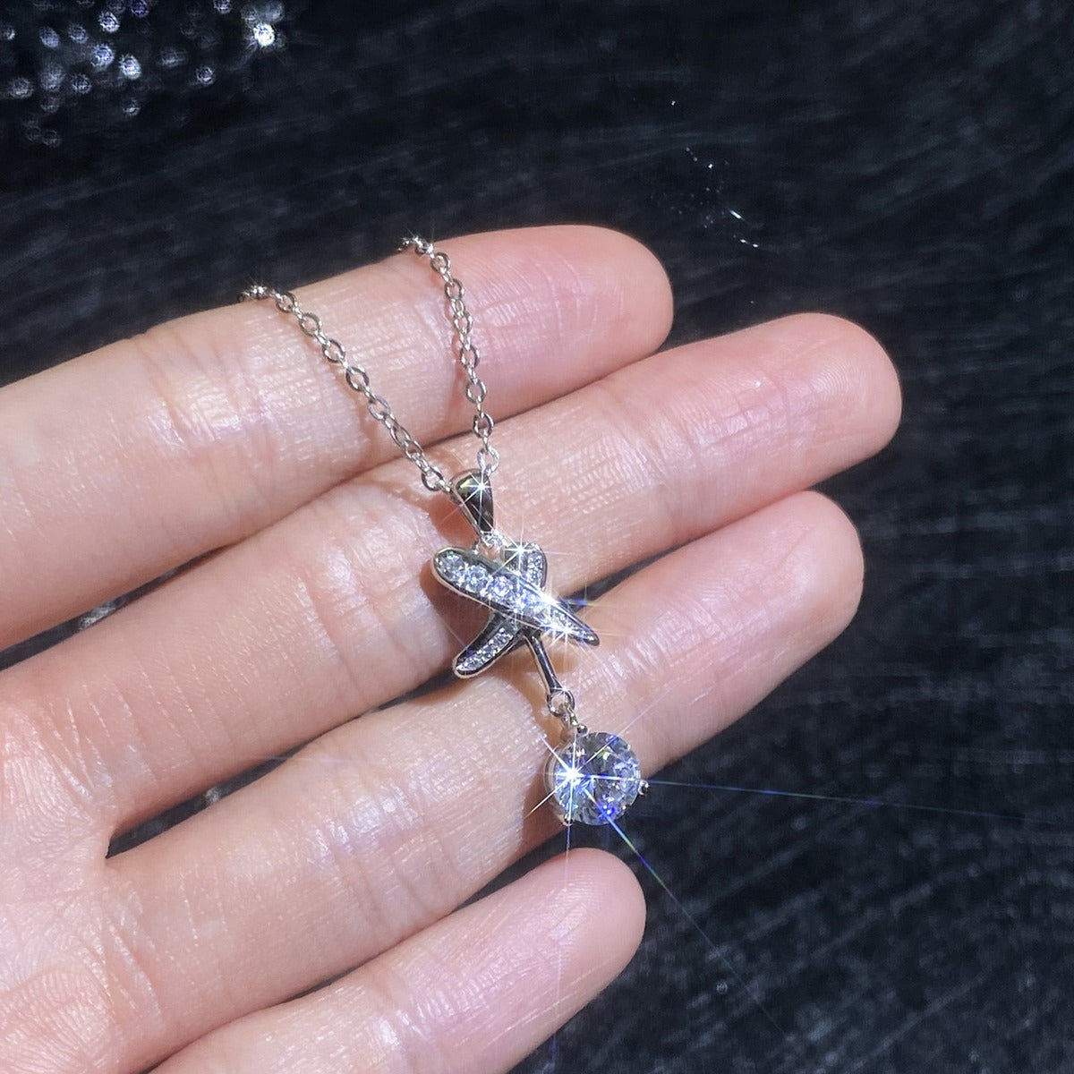Platinum-plated dragonfly moissanite pendant necklace shown in hand