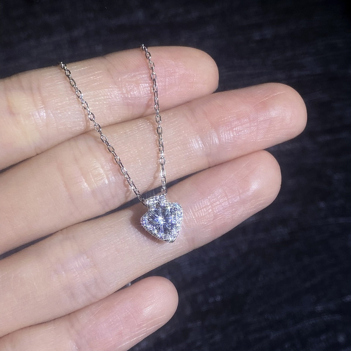 Heart moissanite pendant necklace shown in hand with delicate chain