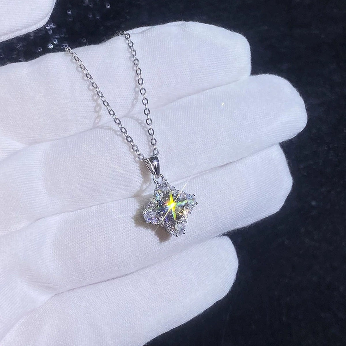 Four-Point Star Round Moissanite Necklace with CZ in Gold-Plated S925 sterling silver handheld close-up showing four-point star pendant with a 1 ct round moissanite and CZ accents and stone setting
